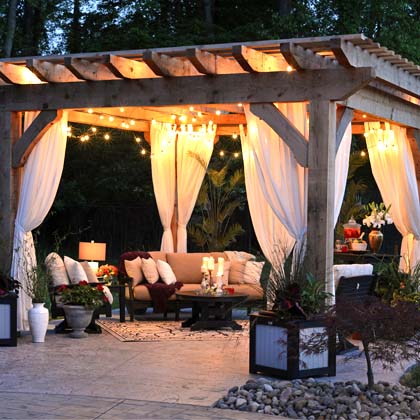 Outdoor seating area with blankets, light fixtures, pillows and plants